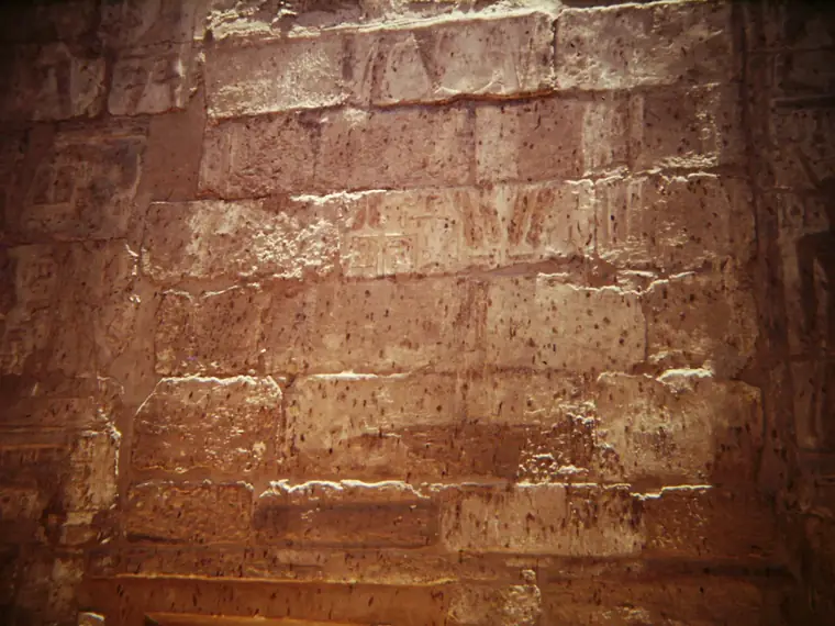 Sandsteinwand im Tempel von Luxor mit verwitterten Reliefs in warmem Licht